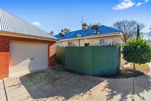 Un immobile residenziale con garage, giardino recintato e un albero.