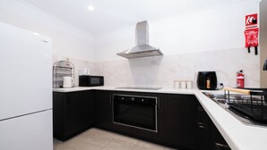 A modern kitchen with a built-in oven, microwave, and a stainless steel range hood.