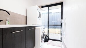 A compact kitchen with a built-in washing machine and a large window.