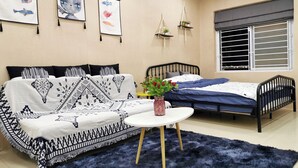 A bedroom with a black and white patterned sofa, a single bed, a round white table with a vase, and wall-mounted decorations. - Localview Balcony-Trainstreet -Netflix-King Bed-Guide book (Hà Nội)