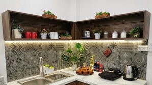 A kitchen with a built-in sink, wooden cabinets, a marble countertop, and decorative plants. - Localview Balcony-Trainstreet -Netflix-King Bed-Guide book (Hà Nội)