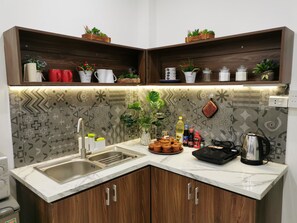 A kitchen with a built-in sink, wooden cabinets, a marble countertop, and decorative plants. - Localview Balcony-Trainstreet -Netflix-King Bed-Guide book (Hà Nội)