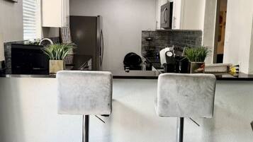 Une cuisine moderne équipée de deux tabourets de bar, d’un réfrigérateur et d’un four à micro-ondes.