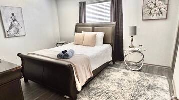 A neatly arranged bedroom with a bed, bedside tables, a lamp, and artwork on the walls.
