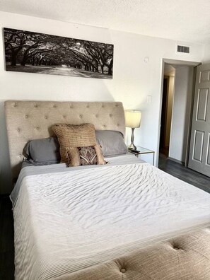 A bedroom with a large bed, a headboard, and a wall-mounted artwork. - Great 3 BR Home Las Colinas, Dallas & Arlington (Irving)