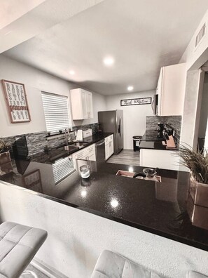 A modern kitchen with a central island, white cabinets, and a stainless steel refrigerator. - Great 3 BR Home Las Colinas, Dallas & Arlington (Irving)