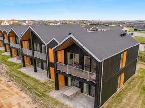 A row of modern, multi-story buildings with balconies and large windows, set in a grassy area with a clear sky. - "Thormund" - 400m from the sea by Interhome (Ringkøbing)