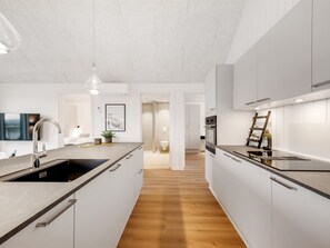A modern kitchen with white cabinetry, a wooden floor, and a built-in oven. - "Thormund" - 400m from the sea by Interhome (Ringkøbing)