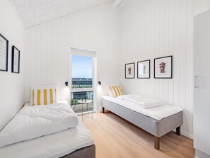 Een slaapkamer met twee bedden, een balkon en lijstwerken aan de muur.