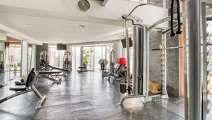 Ein modernes Fitnessstudio mit unterschiedlichen Trainingsgeräten, großen Fenstern und einem aufgeräumten, großzügigen Raum.