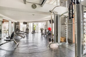 Ein modernes Fitnessstudio mit unterschiedlichen Trainingsgeräten, großen Fenstern und einem aufgeräumten, großzügigen Raum.