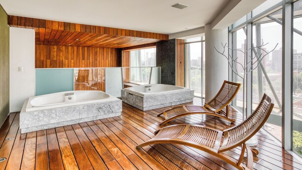 Ein modernes Badezimmer mit zwei großzügigen Badewannen, Holzböden und Blick durch große Fenster.