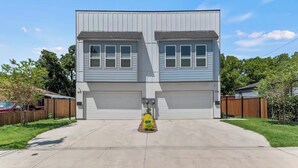 Un immeuble résidentiel à deux étages, doté d’un garage, d’une allée et d’un petit jardin.