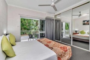 A hotel room with a bed, a balcony with a view, a ceiling fan, and a sliding door leading to an outdoor area. - Barrier Townhouse - Pool & Walk to Beach (Port Douglas)