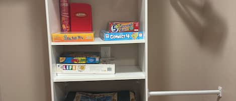 A white bookshelf with various board games and a quilt.