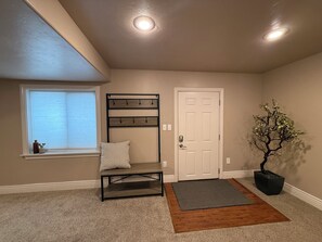 A hallway with a bench, a door, a potted plant, and a window with blinds. - Spacious 3BR SLC, Skiing & Silicon Slopes (South Jordan)