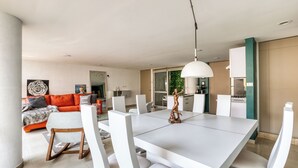 A modern dining area with a white table and chairs, a hanging light fixture, and a view into the living room with a sofa and cushions. - Reforma Elegance · A Pasos del Ángel (Ciudad de México)