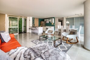 Een moderne woonkamer met een glazen salontafel, een bank en een eethoek met stoelen.