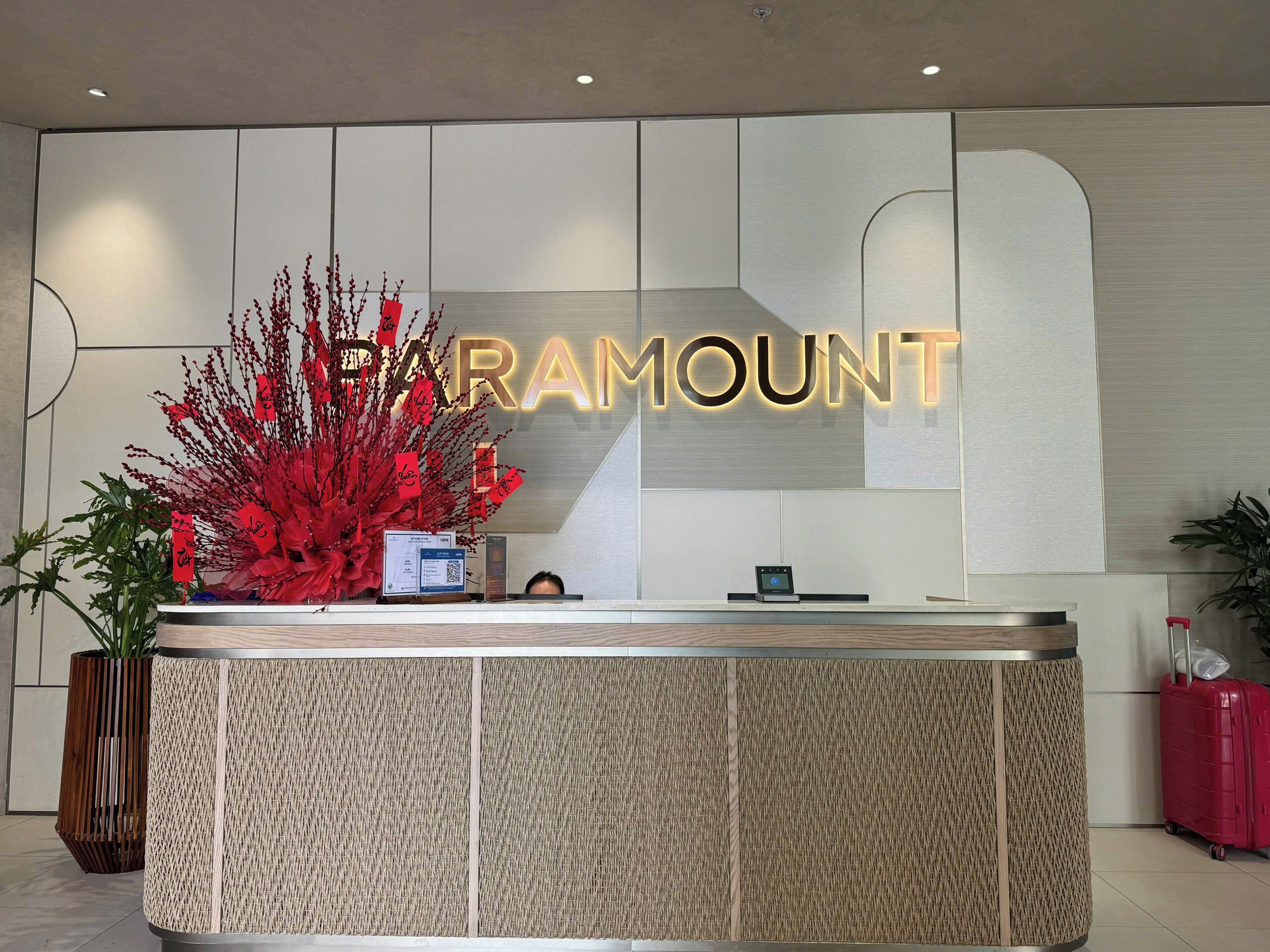 A reception desk with a sign that reads 'PARAMOUNT' and a decorative red plant arrangement.