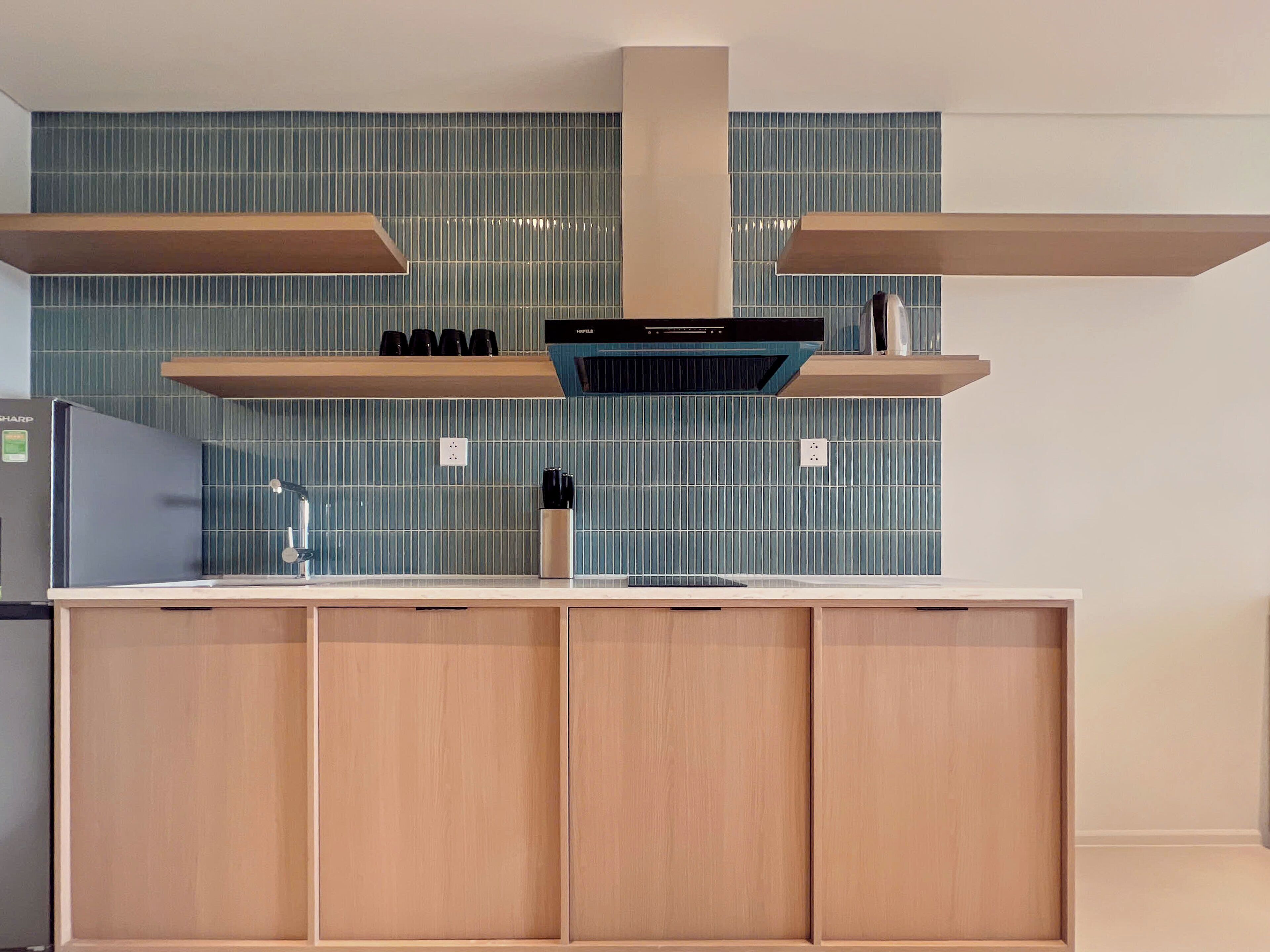Eine moderne Küche mit einer zentralen Kochinsel, Holzschränken und einer dunkelblauen Küchenrückwand.