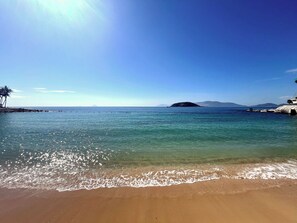 Una playa con agua cristalina, una orilla arenosa y una isla en la distancia.