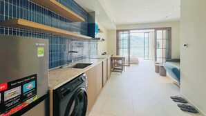 Una cocina moderna con un refrigerador Sharp, una lavadora Aquia y un comedor con vista.