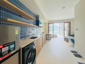 A modern kitchen with a Sharp refrigerator, an Aquia washing machine, and a dining area with a view.
