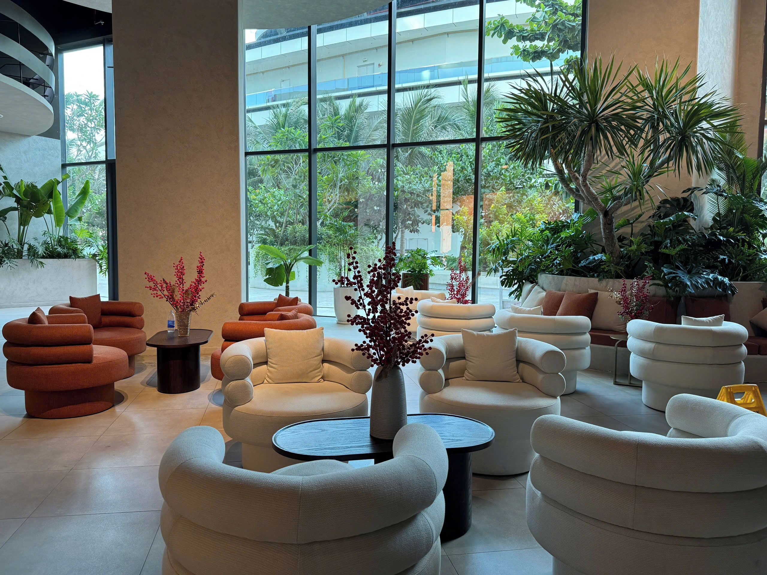 A modern lounge area with multiple seating options, large windows, and indoor plants.