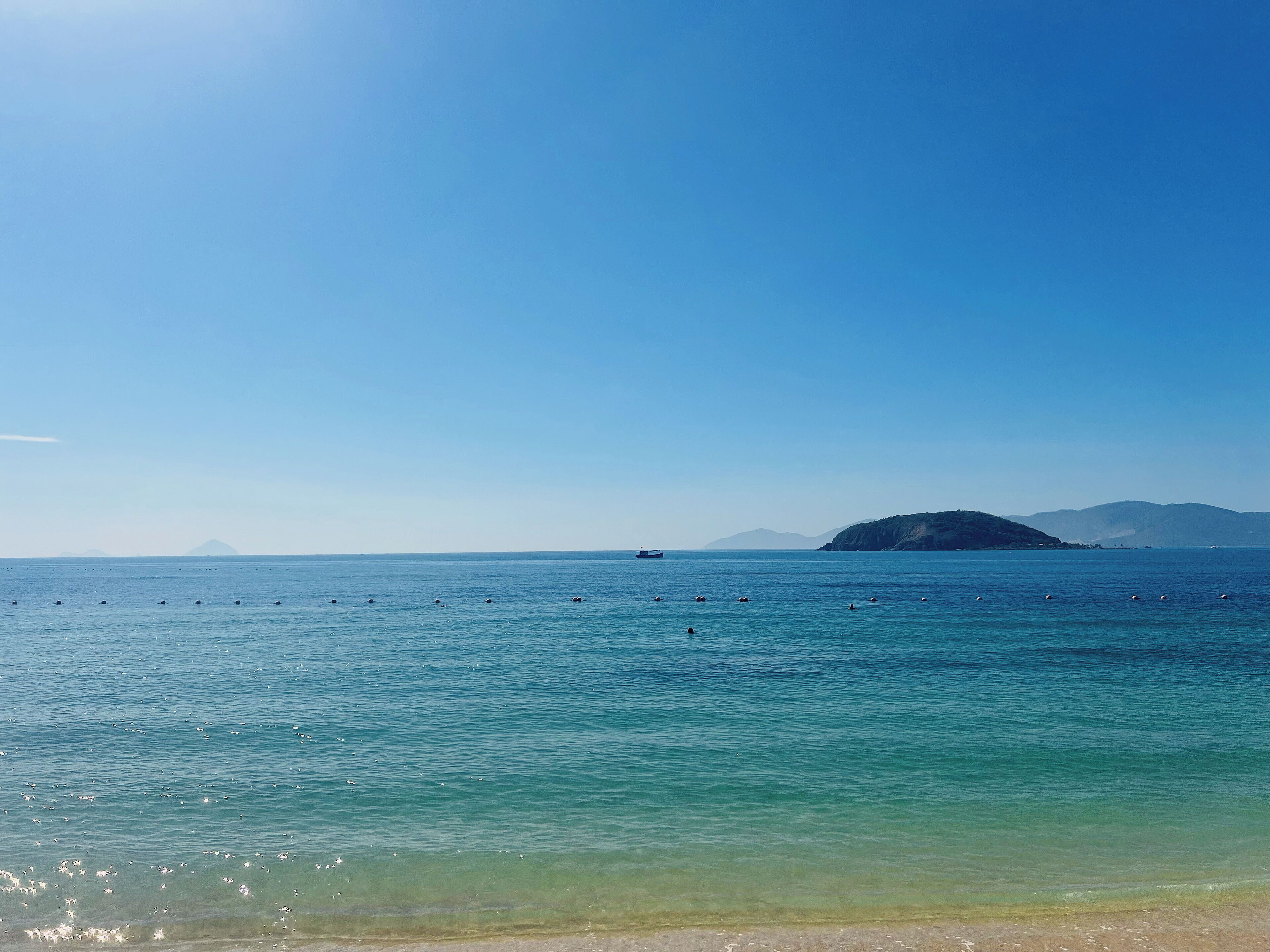 Une vue dégagée sur une mer calme, avec une montagne lointaine et un bateau.