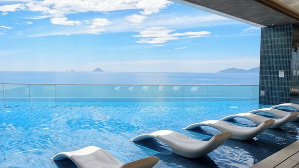 A pool with clear blue water, a tiled deck, and lounge chairs. - Bai Tien Ocean Front Residences (Bac Nha Trang)