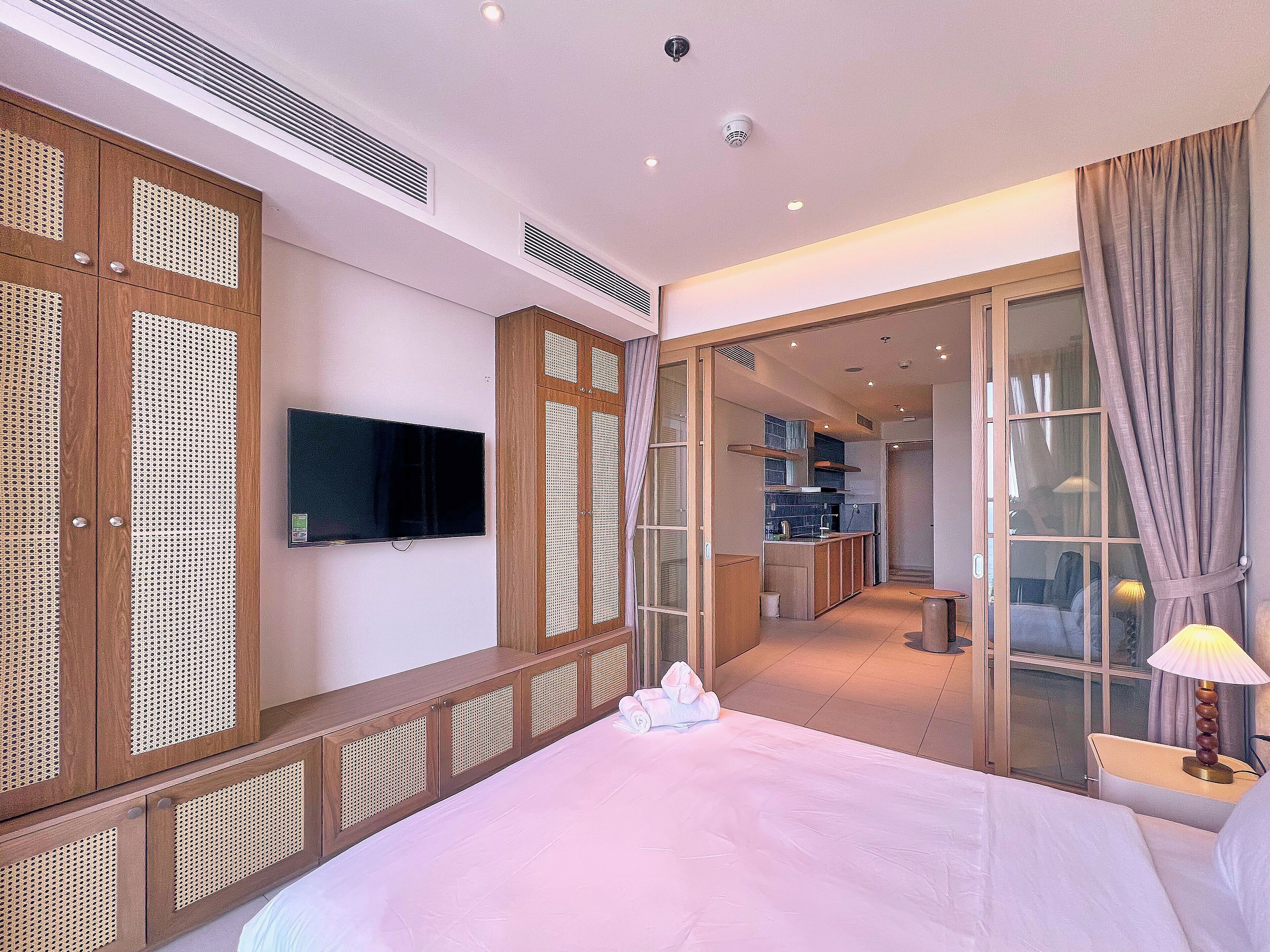 A hotel room with a bed, a television, a bathroom, and a kitchenette.