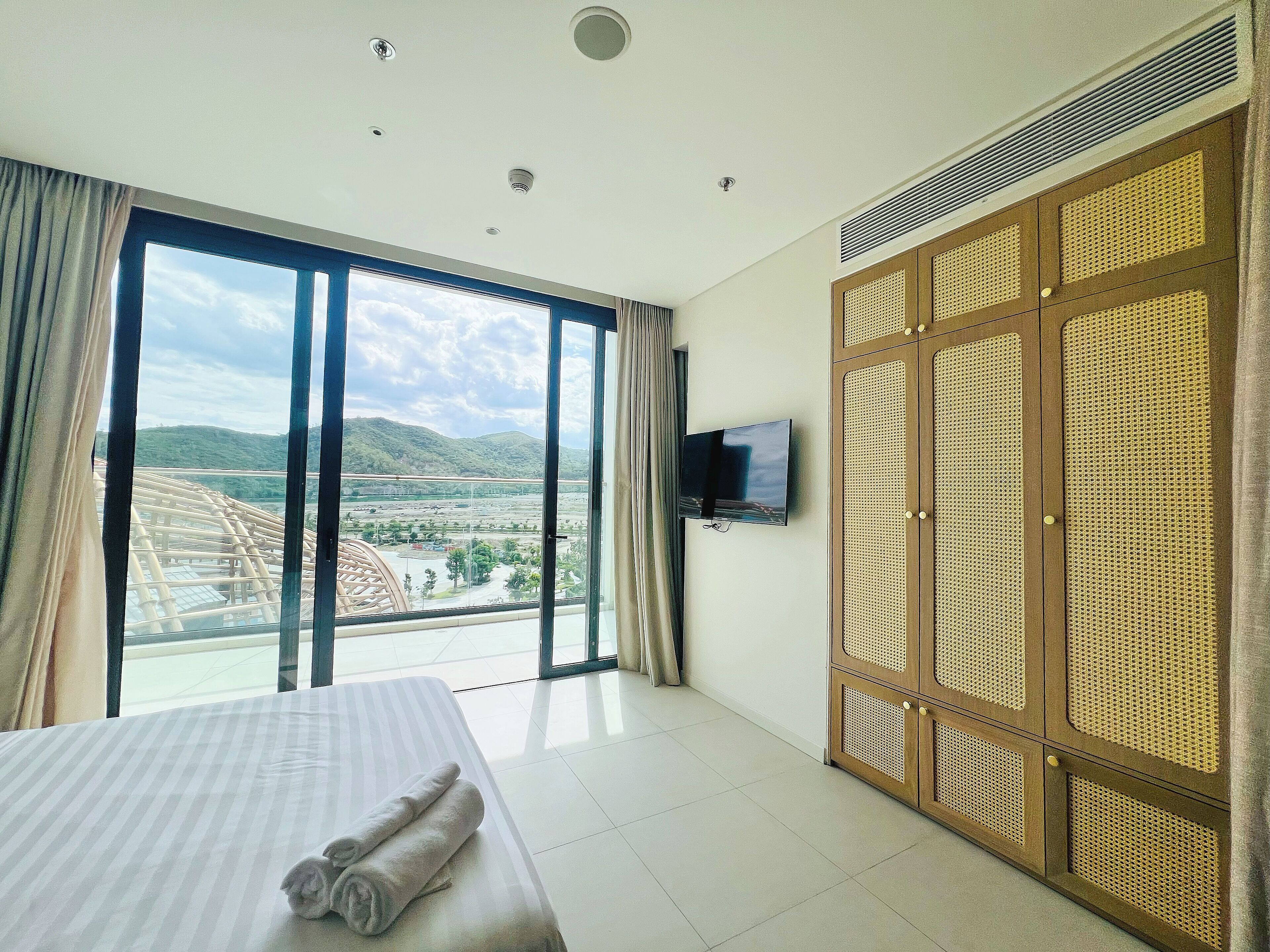 A hotel room with a large bed, a television, and a view of a landscape through the window.
