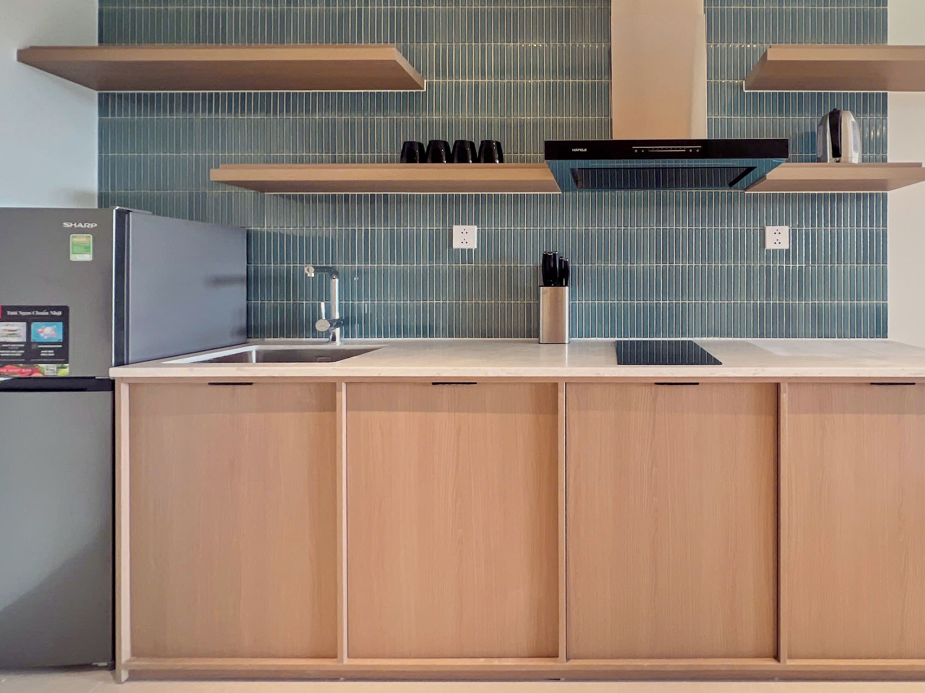 Una cocina moderna con refrigerador integrado, un lavamanos y armarios de madera.