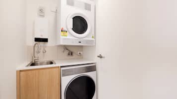 A compact laundry area with a washing machine, a sink, and a towel rack.