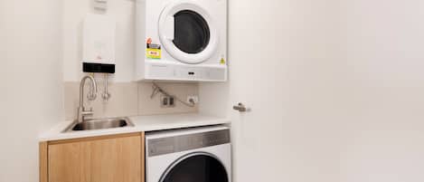 A compact laundry area with a washing machine, a sink, and a towel rack.