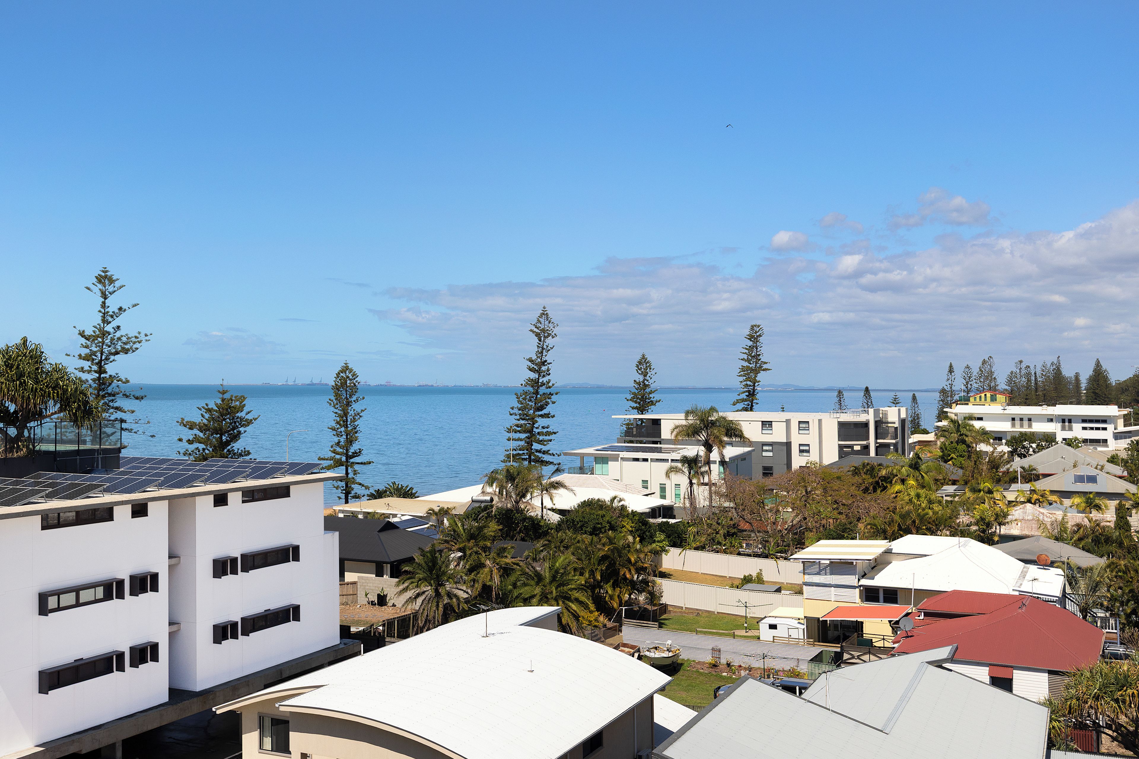 Un quartier résidentiel situé sur la côte, avec des bâtiments modernes, une vue sur la mer et un ciel dégagé.