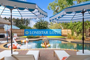 Un espace piscine avec des chaises longues, des bouées en forme de cygne et des parasols. Une pancarte indique : « LONESTAR LOTUS ».