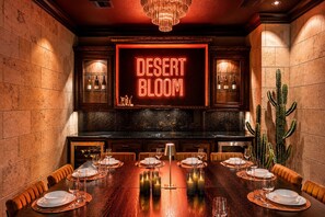 A restaurant with a neon sign reading 'DESERT BLOOM,' wooden walls, a long dining table set with plates and glasses, and a cactus plant. - Epic TX Stay: Pickleball•Golf Sim•Theater•Sleeps24 (Spring)