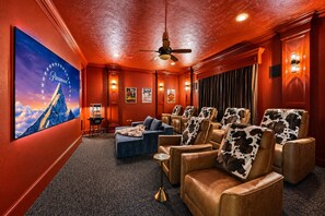A home theater room with leather recliners, a blue sofa, and a ceiling fan. - Epic TX Stay: Pickleball•Golf Sim•Theater•Sleeps24 (Spring)