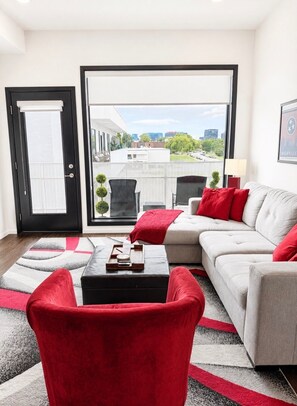 Een moderne woonkamer met een bank, een rode fauteuil en een salontafel.
