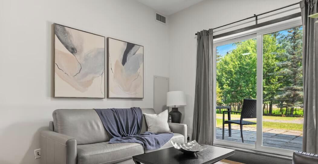 A modern living room with a grey sofa, a coffee table, and two abstract paintings on the wall.