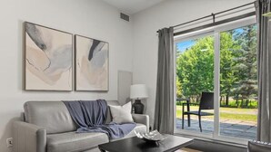 Una sala de estar moderna con un sofá gris, una mesa de centro y dos cuadros abstractos en la pared.