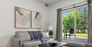 A modern living room with a grey sofa, a coffee table, and two abstract paintings on the wall. - Luxury Rockies Escape - Pool & HotTub - King Bed - AC! (Canmore)