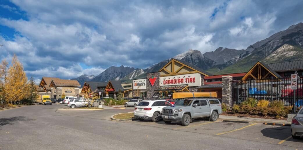 A parking lot with several cars, a Canadian Tire store, and a mountain backdrop.