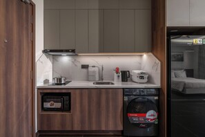 A compact kitchen with a built-in dishwasher, a rice cooker, and a coffee maker. - Eli Living Apartment (Da Nang)