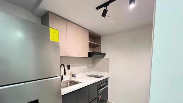 A modern kitchen with a built-in refrigerator, a sink, and a stove. - Bella Vista Luxury Apartments Pool & Gym (Panamá)