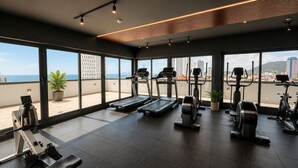A gym with cardio machines, a rowing machine, and a view of the city. - Bella Vista Luxury Apartments Pool & Gym (Panamá)
