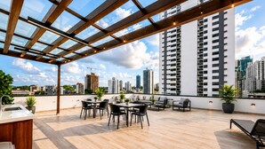 A rooftop terrace with a wooden floor, outdoor seating, and potted plants. - Bella Vista Luxury Apartments Pool & Gym (Panamá)