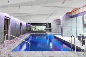 An indoor swimming pool with a clear view of the pool area, surrounded by walls and a ceiling with a geometric design. - Elegant Melbourne CBD Getaway - Pool & Gym Access (Melbourne)