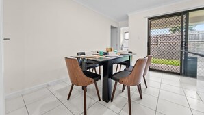 Een eetgedeelte met een tafel voor vier personen, stoelen en uitzicht door een glazen deur op een buitenruimte.